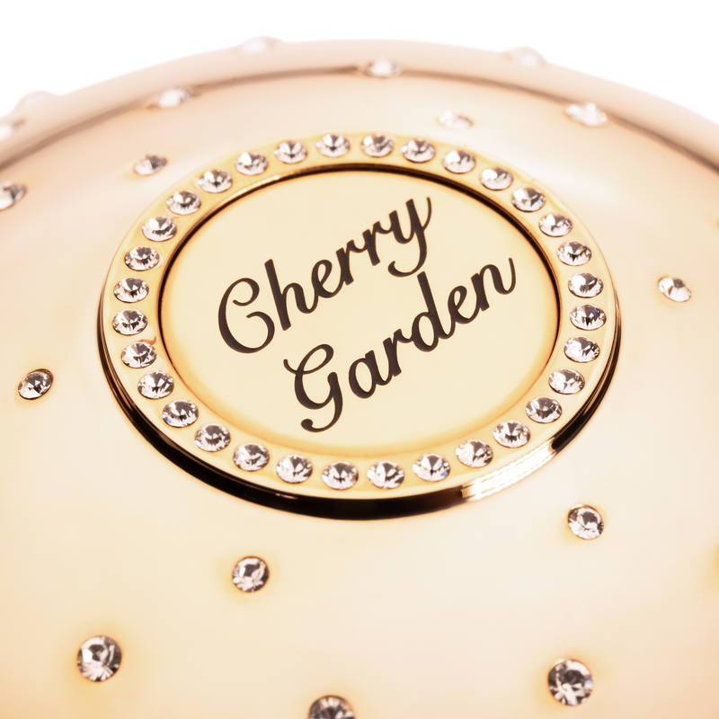 Gold compact with 'Cherry Garden' text and rhinestone embellishments