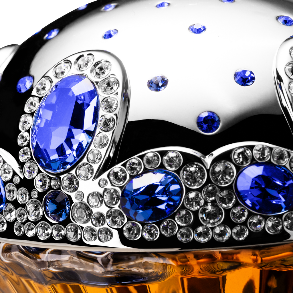 Decorative object with blue and clear gemstones on a reflective surface